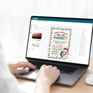 Puede incluir: Una pantalla de computadora port&aacute;til que muestra una invitaci&oacute;n a una fiesta de Navidad con un Pap&aacute; Noel de dibujos animados. La invitaci&oacute;n dice "Calling Santa's favorite HO HO HOS!" y "Let's eat, drink, and be merry!"
