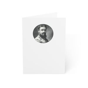 May include: A white greeting card with a black and white portrait of a man with a beard in a circular frame. The card is folded and has a blank interior.