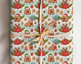 May include: A wrapped gift with a festive Christmas-themed pattern. The wrapping paper features a repeating design of capybaras wearing Santa hats, gingerbread cookies, holly, and Christmas trees. A tan ribbon is tied around the gift.