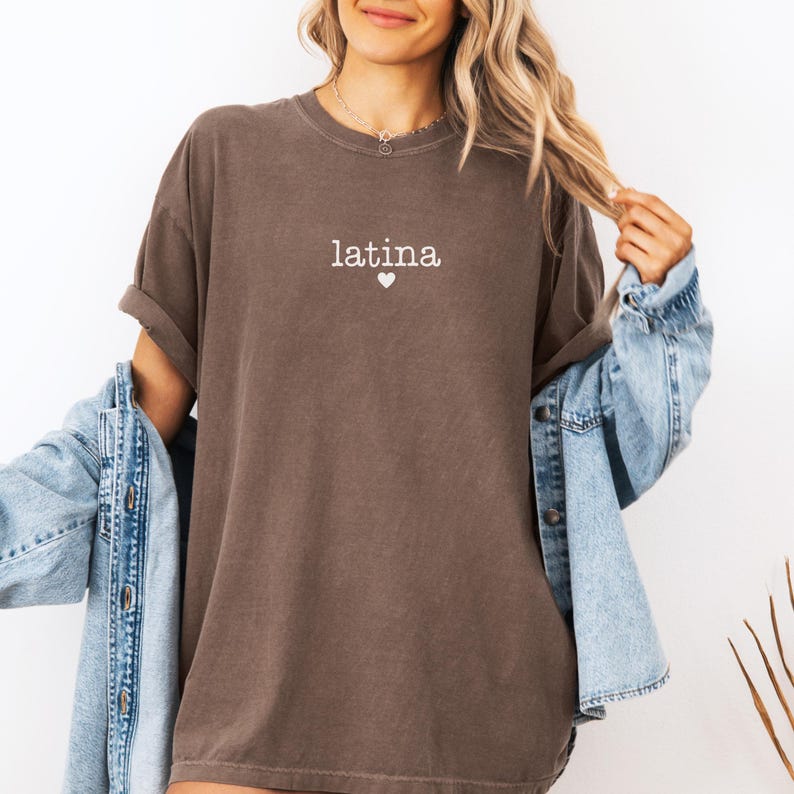 May include: A brown oversized t-shirt with the word "latina" and a small heart printed in white on the front.