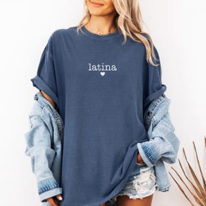 May include: A blue oversized t-shirt with the word "latina" and a small heart printed on the front.