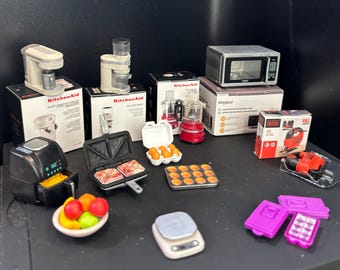 May include: A collection of miniature kitchen appliances and food items including a KitchenAid coffee maker, food processor, Whirlpool microwave, Black and Decker jigsaw, air fryer, sandwich press, egg carton, muffin tin, fruit bowl, and scale.