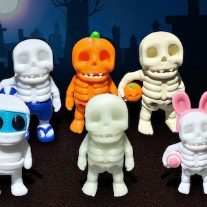 May include: A collection of small skeleton figurines, each with unique costumes and accessories. The figures include a pumpkin, astronaut, bunny, and Santa, all in a spooky graveyard setting. The figurines are approximately 3 inches tall.