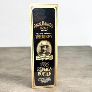 May include: A replica bottle of Jack Daniel's Old No. 7 Brand Whiskey. The black and gold label features the brand name, a portrait of Jack Daniel, and the text "1895 Replica Bottle."