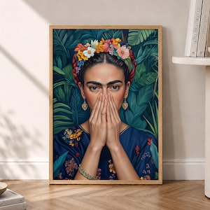 以下が含まれることがあります： 色とりどりの花冠をつけた編み込みのダークヘアの人物を描いた額入りアートプリント。人物は柄入りのダークブルーのトップスとハート型のゴールドイヤリングを身につけ、緑豊かな葉を背景に顔の近くで両手を組んでいる。