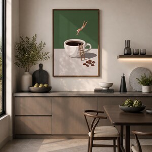 May include: A framed wall art print featuring a surreal illustration of a person diving into a large white coffee cup. A wooden ladder leans against the cup, which sits on a surface with scattered coffee beans against a dark green background.