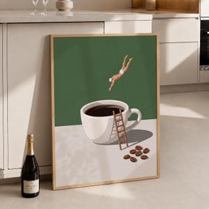 May include: A framed wall art print featuring a white coffee cup filled with dark liquid on a light surface. A small figure in white swimwear dives towards the cup, while a wooden ladder leans against the side. Several brown coffee beans lie nearby.