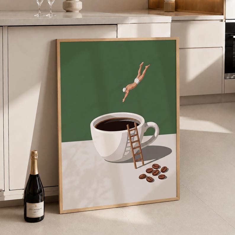 May include: A framed wall art print featuring a white coffee cup filled with dark liquid on a light surface. A small figure in white swimwear dives towards the cup, while a wooden ladder leans against the side. Several brown coffee beans lie nearby.