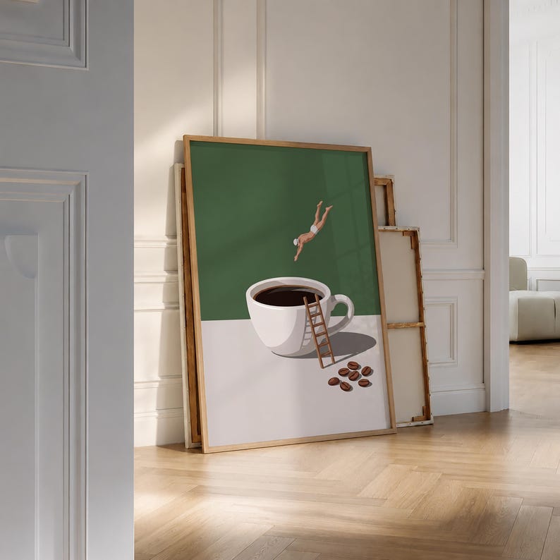 May include: A framed wall art print featuring a white coffee cup filled with dark liquid on a light surface. A small figure in white swimwear dives into the cup, while a wooden ladder leans against the side. Several coffee beans lie nearby.