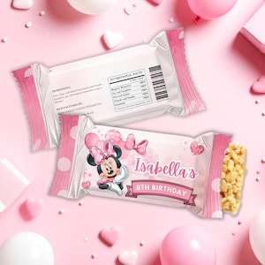 May include: Two pink and white candy bar wrappers with a Minnie Mouse design. One wrapper is partially open, revealing a puffed rice treat. The wrappers are personalized with the text "Isabella's 8th Birthday".