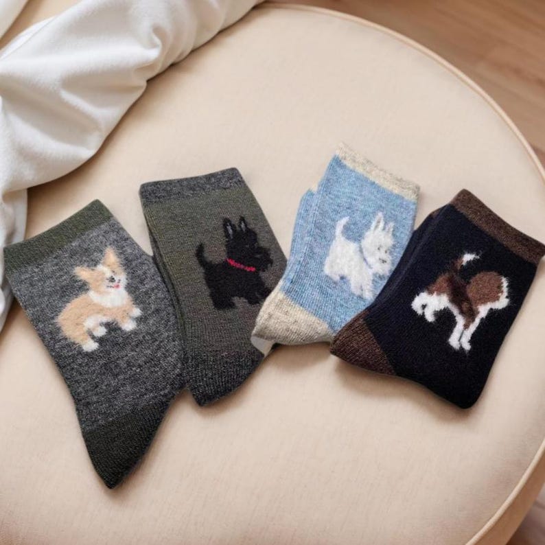 Pu&ograve; includere: Quattro paia di calzini con disegni di cani. I calzini presentano un corgi, uno Scottish terrier, un West Highland white terrier e un beagle. I calzini sono in tonalit&agrave; di grigio, blu e nero.