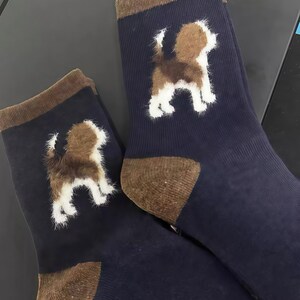 Pu&ograve; includere: Un paio di calzini blu navy con tallone e polsini marroni. Ogni calzino presenta una grafica di cane marrone e bianco soffice. I calzini sono realizzati in un materiale morbido e sono adatti all'uso quotidiano.