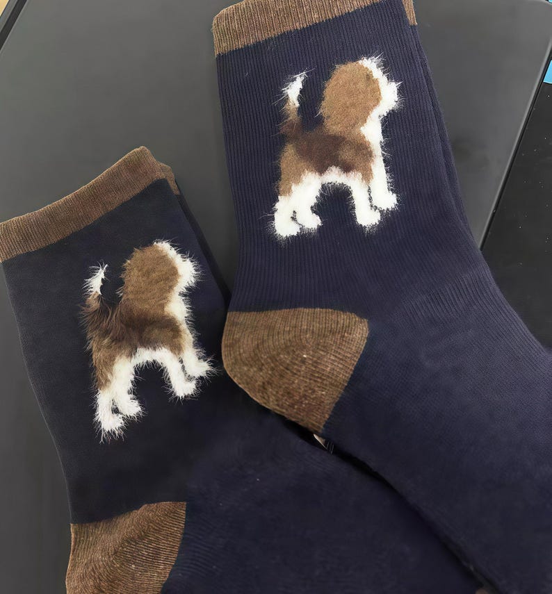 Pu&ograve; includere: Un paio di calzini blu navy con tallone e polsini marroni. Ogni calzino presenta una grafica di cane marrone e bianco soffice. I calzini sono realizzati in un materiale morbido e sono adatti all'uso quotidiano.