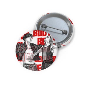 Peut inclure: Épinglette blanche avec une illustration en noir et rouge de deux personnes. L'une porte une veste avec le texte "KID STU" et l'autre un débardeur. Le fond porte le texte "BODY REBEL" en rouge.