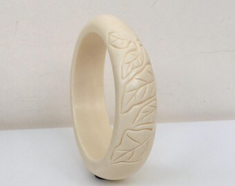 Bracciale rigido vintage in lucite, con intagli floreali color avorio.