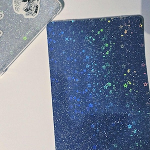 以下が含まれることがあります： 散らばった虹色の星のパターンを持つ、濃い青色のホログラフィックステッカーです。