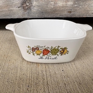 May include: A white ceramic mug with a black handle and the text "But First, Coffee" in a black, bold font. The mug is on a white surface.