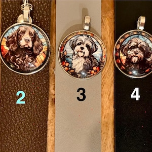May include: Five round silver pendants with dog portraits. Each pendant features a different breed of dog, with colorful stained-glass style backgrounds. The pendants are displayed on various colored leather straps.