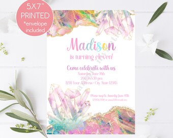 May include: A 5x7 inch printed invitation with a crystal theme. The invitation is pink, blue, and purple with gold glitter accents. The text on the invitation reads "Madison is turning eleven! Come celebrate with us Saturday, June 10th 2:00-5:30 pm 1234 Your Address - City State 12345 Please rsvp to Anna by June 10th 1234567000 or anna@email.com"