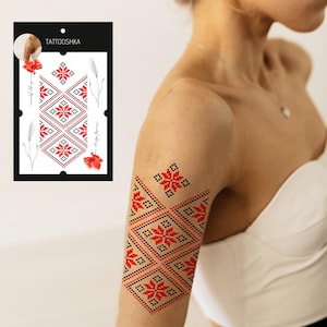 May include: A temporary tattoo featuring a red and black geometric pattern. The pattern is inspired by traditional Ukrainian embroidery. The tattoo is applied to a person's upper arm.