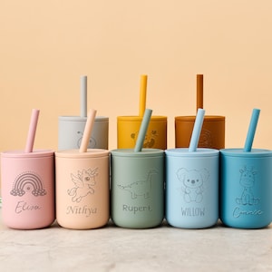 Può includere: Un set di sette tazze in silicone colorate con coperchi e cannucce. Ogni tazza è di un colore pastello diverso e presenta un design inciso unico, tra cui un arcobaleno, un unicorno, un dinosauro, un koala e una giraffa. Nomi incisi.
