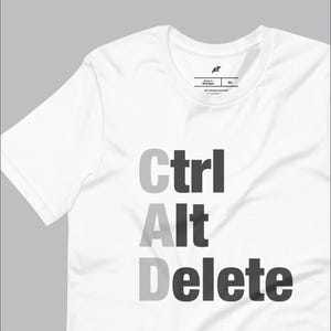 Puede incluir: Camiseta blanca con el texto "Ctrl Alt Delete" impreso en letras negras y grises.