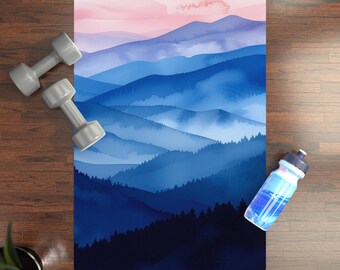 May include: A blue and pink watercolor yoga mat with a mountain range design. The mat is on a wooden floor with a water bottle and two weights.