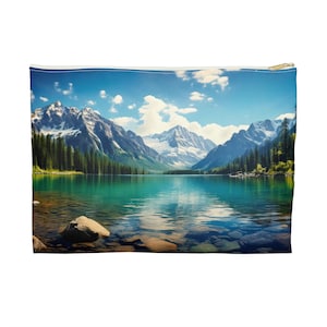 May include: A rectangular zippered pouch featuring a scenic landscape of a mountain lake. The design showcases snow-capped mountains, evergreen trees, and a clear turquoise lake under a bright blue sky with fluffy white clouds. The pouch has a gold-colored zipper.