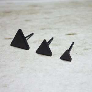 Puede incluir: Tres pendientes de tri&aacute;ngulo negro de diferentes tama&ntilde;os. Los pendientes son de metal y tienen un dise&ntilde;o simple y minimalista.