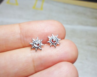 May include: A pair of silver sun earrings with a small clear rhinestone in the center of each sun.