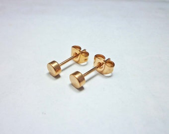 May include: A pair of gold-toned stud earrings with a simple round design.