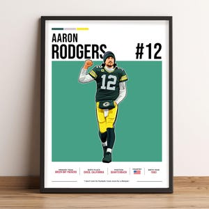 May include: Framed art print with an illustration of Aaron Rodgers in a Green Bay Packers uniform. The print includes the player's name, jersey number 12, and biographical details. The background is a teal green colour.