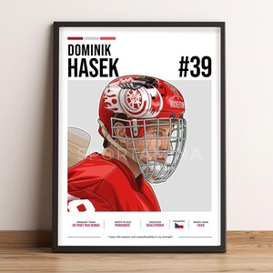 May include: A framed print featuring Dominik Hasek in a red hockey uniform and helmet. The helmet has a white and red design. The print includes the text "DOMINIK HASEK #39" and details about his primary team, birth place, position, country, and birth year.