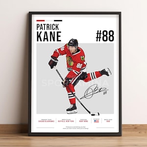 Op de afbeelding: Een ingelijste poster met een illustratie van ijshockeyspeler Patrick Kane in een rood, zwart en wit Chicago Blackhawks-uniform, met een hockeystick. De tekst bevat zijn naam, nummer 88, een handtekening en spelersstatistieken.