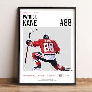 Może przedstawiać: Oprawiony wydruk przedstawiający Patricka Kane'a w hokejowym uniformie Chicago Blackhawks, numer 88. Czerwona koszulka ma czarne i białe akcenty. Tekst zawiera jego imię, drużynę, dane urodzenia i cytat.