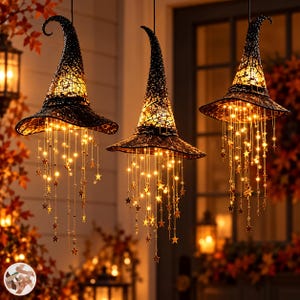 May include: Three hanging black witch hats featuring a textured, lace-like surface and pointed, curved tops. Each hat is illuminated from within and adorned with cascading strings of warm white LED lights and small metallic star-shaped charms.