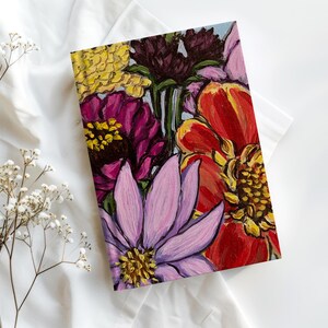 May include: A close-up of a painted floral design featuring a variety of flowers in shades of pink, red, yellow, and purple. The flowers are arranged in a bouquet and are painted in a realistic style.