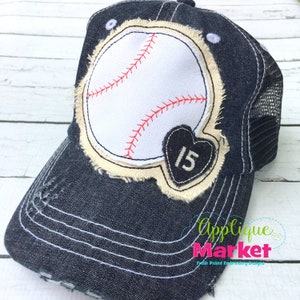 May include: Distressed denim baseball cap featuring a white baseball design with red stitching. A black heart with the number 15 is on the side. The cap has a mesh back and a curved brim.