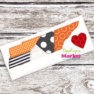 May include: A white fabric with an orange, black, and white patchwork design of the state of Tennessee. A red heart is stitched to the right of the state outline. The text "Applique Market" is visible in the lower right corner.