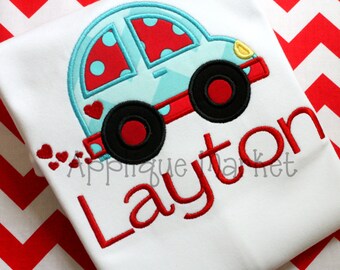 May include: A white t-shirt with a blue and red car design and the name "Layton" embroidered in red.