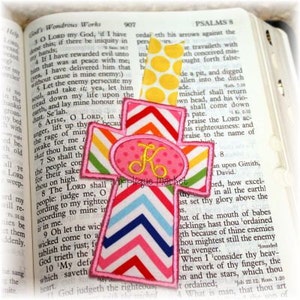 May include: A pink and rainbow chevron cross bookmark with a pink oval monogrammed with the letter "K".