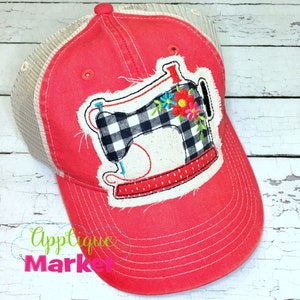 Pode incluir: Um boné de caminhoneiro vermelho e branco com uma aplicação de máquina de costura xadrez preta e branca. A aplicação tem um design floral com flores rosa, amarelas e azuis. O boné tem uma parte de trás de malha e uma aba curva.