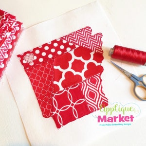 May include: Red and white patchwork fabric design in the shape of the state of Arkansas. The fabric is stitched together with a white thread. The design includes a small heart in the upper left corner. The fabric is on a white background. The text "Applique Market" is in the lower right corner of the image. The text "Fresh Picked Embroidery Designs" is below the text "Applique Market".