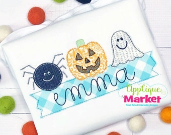 May include: A blue and white checkered banner with the name "emma" embroidered on it.  The banner has a spider, a pumpkin, and a ghost embroidered on it.  The text "Applique Market" is also embroidered on the banner.