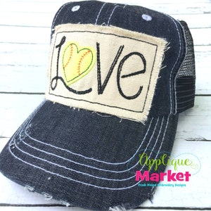 May include: A black and white trucker hat with a white patch that says "LOVE" with a yellow softball in a heart shape. The hat has a mesh back.