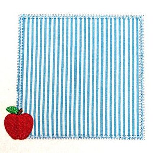 May include: A blue and white striped fabric square with a red embroidered apple in the bottom left corner.