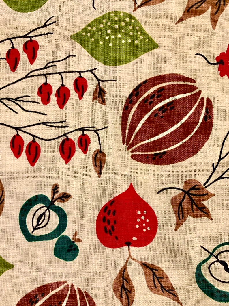 May include: A beige fabric with a repeating pattern of red, green, and brown fruits and leaves. The fruits are stylized and resemble apples, pears, and gourds. The leaves are brown and green.