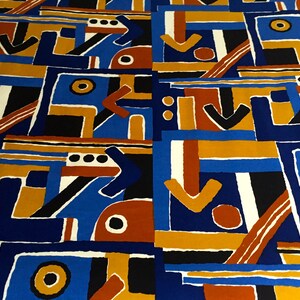 May include: Abstract geometric pattern fabric in blue, orange, brown, black, and white. The pattern features arrows, circles, and squares.