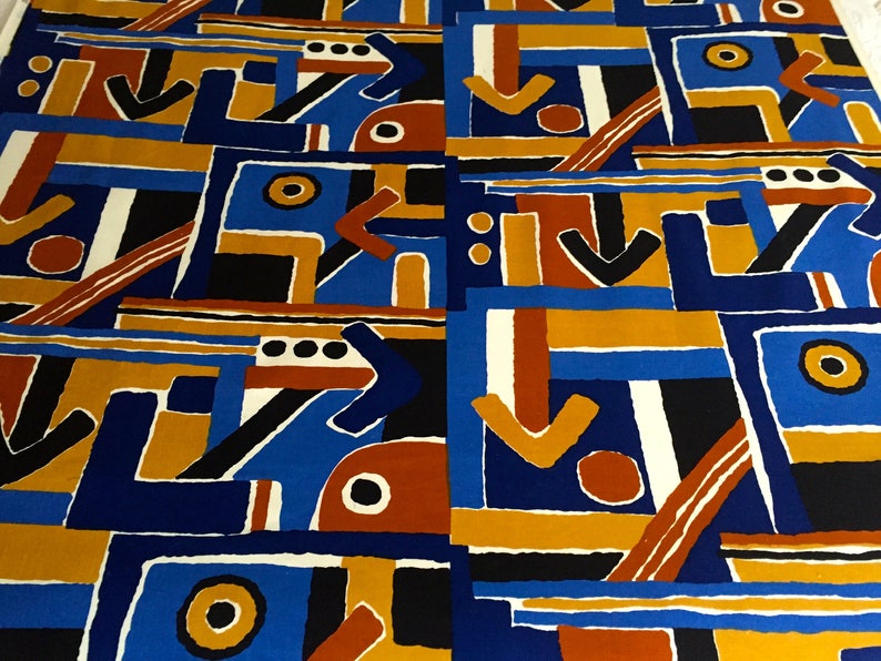 May include: Abstract geometric pattern fabric in blue, orange, brown, black, and white. The pattern features arrows, circles, and squares.