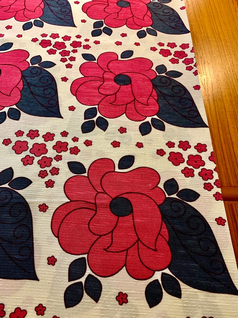 May include: White fabric with a repeating pattern of large pink flowers with dark blue leaves and small pink flowers.